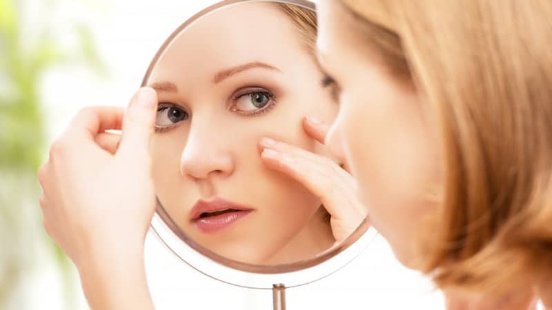 Ciri CIri Cream Pemutih Wajah Berbahaya - Perempuan Mengecek Wajah di Cermin